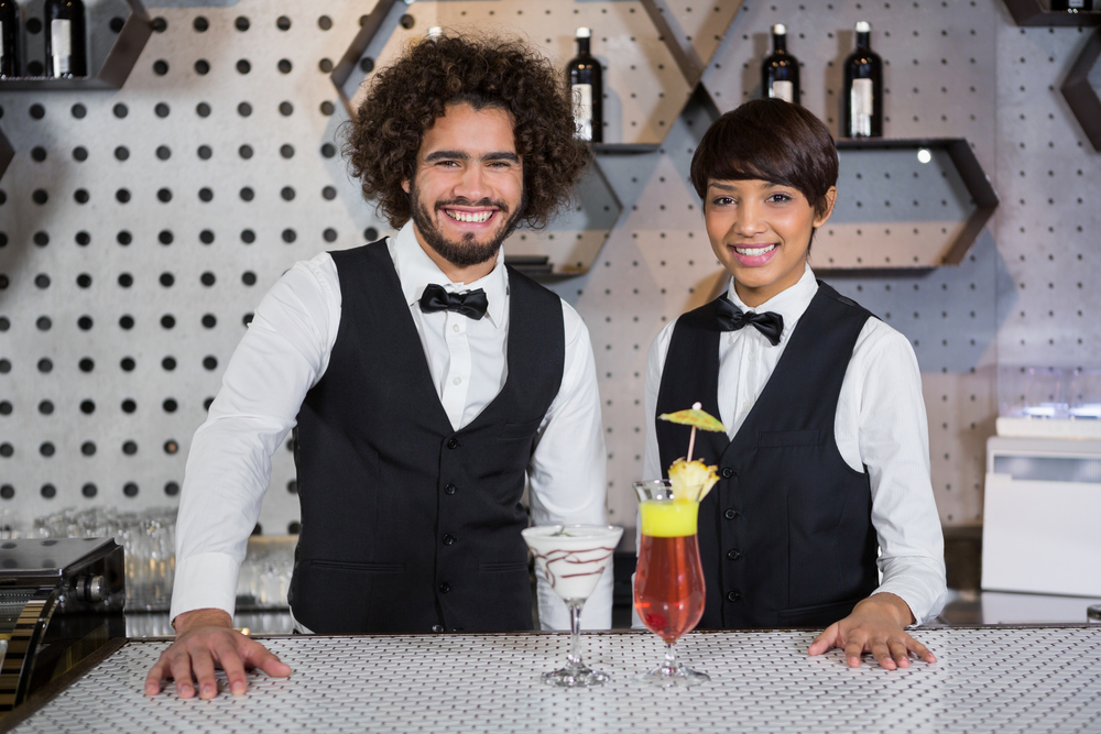 Smiling waiters standing at bar counter