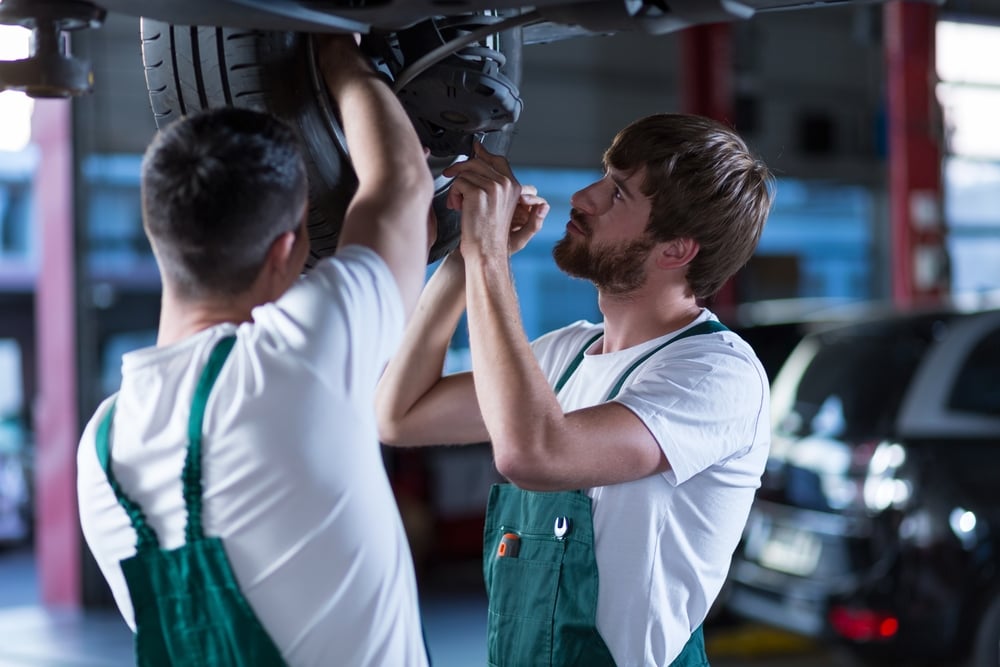 Auto mechanics working together a lifted car